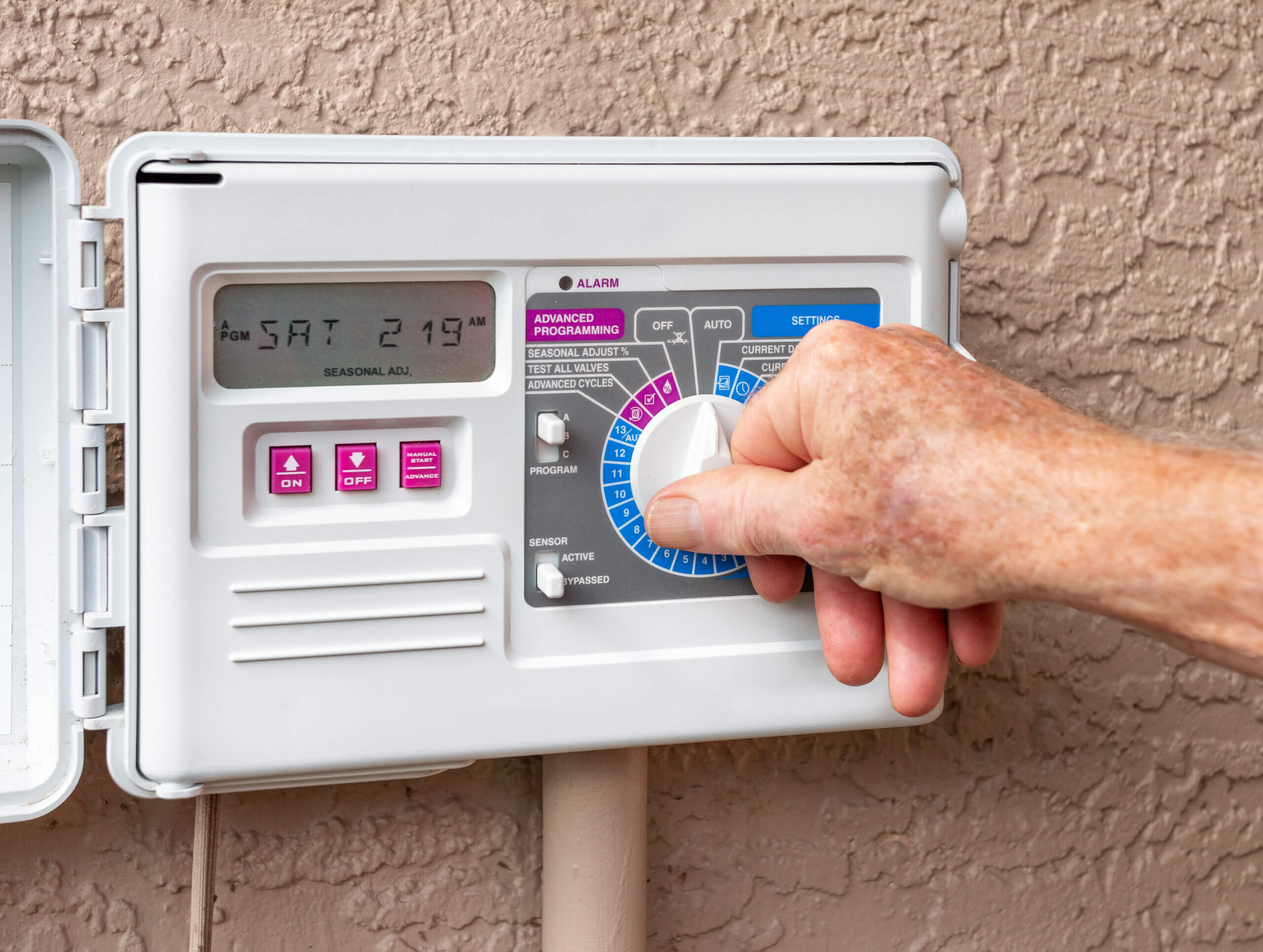 A landscape designer adjusting setting on a lawn irrigation system
